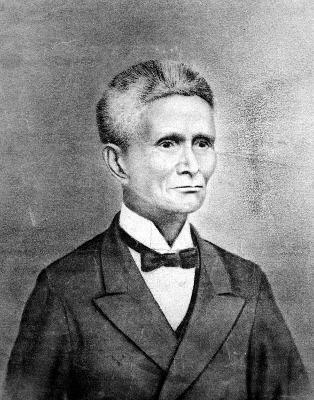 A black and white photo-realistic portrait of a senior Japanese man with bristly, salt and pepper hair, a slight smile, wearing a suit jacket, and a starched collar shirt tied with a bowtie.